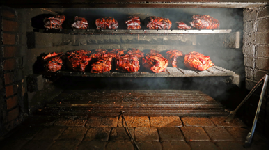 racks of meat grilling inside a brick oven 